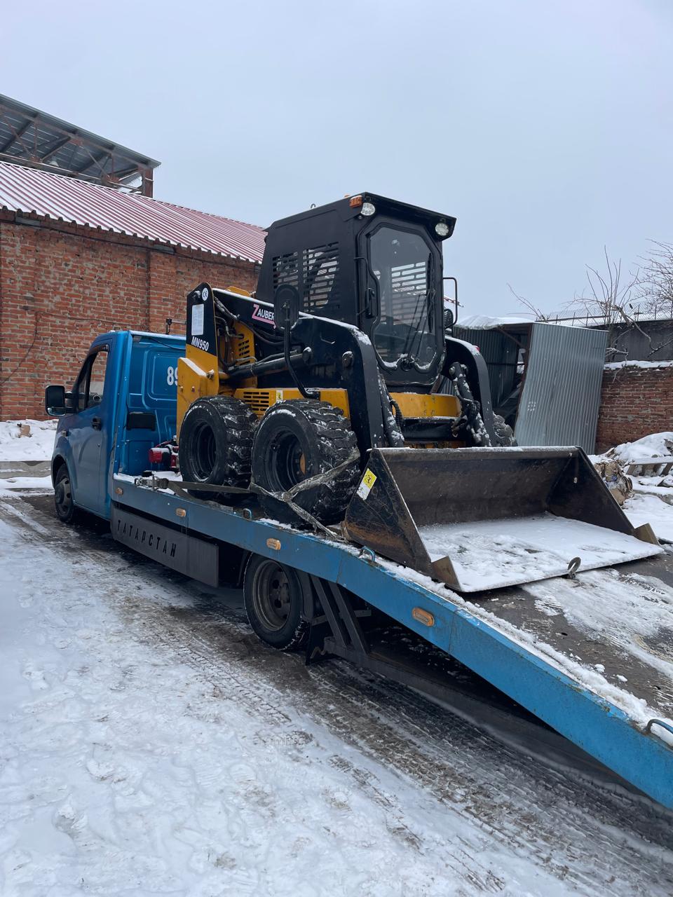 Погрузчик на платформе эвакуатора зимой