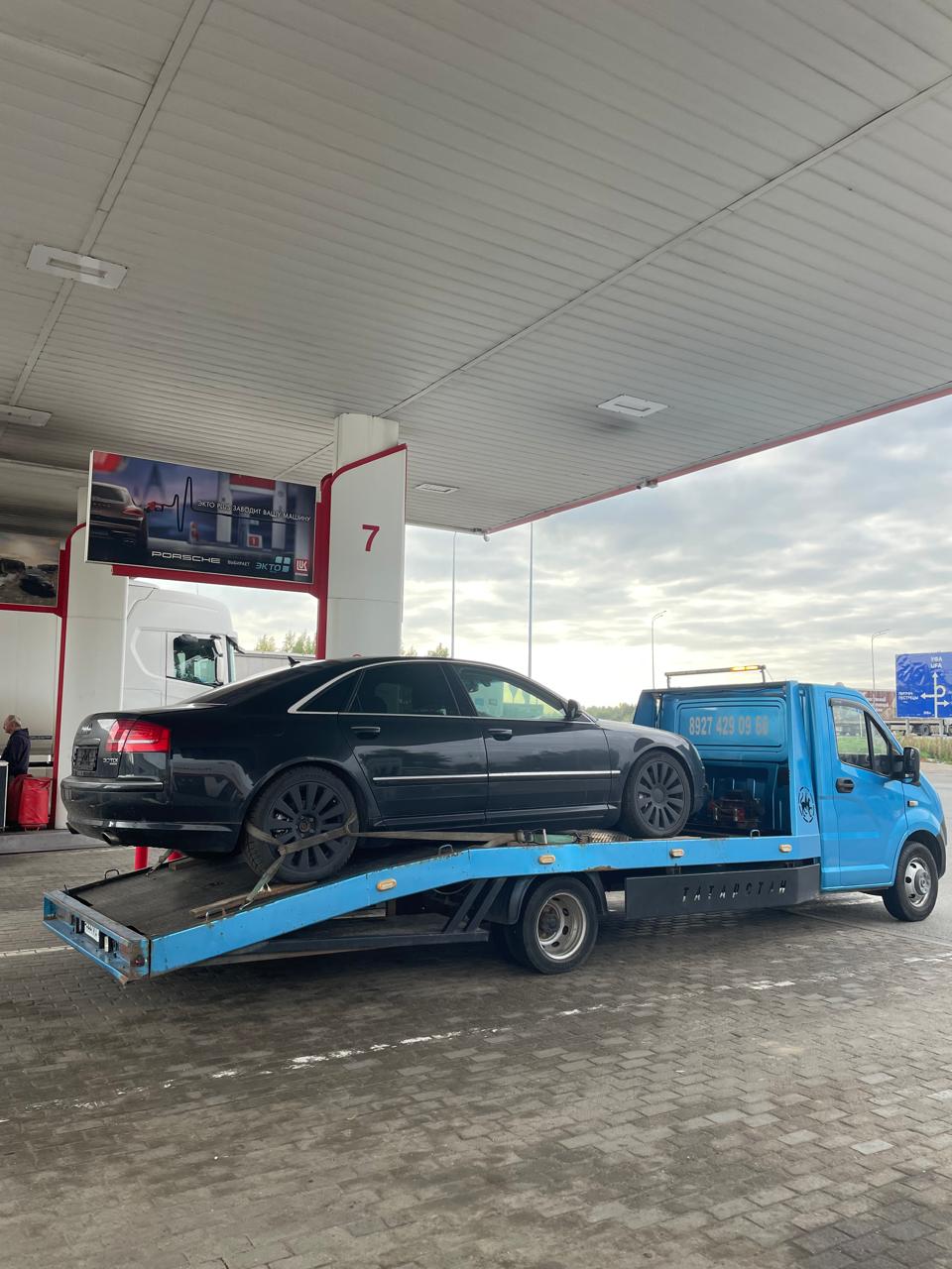 Черный седан на эвакуаторе на заправке