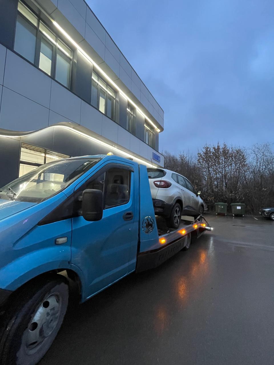 Кроссовер на эвакуаторе у здания вечером